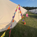 Bell tents with colourful festival-themed bunting on a grassy field 