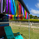 Colourful streamers hanging from a structure with a teal chair and outdoor setting.