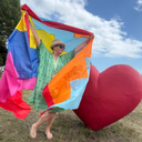 Person holding a colourful flag with a large red heart in the background