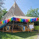 Tipi tent with rainbow decorations and tables set up outdoors