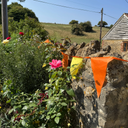 Floral arrangements and colourful bunting on a stone wall with a rural landscape in the background.