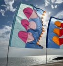 Colourful heart-shaped flags waving in the wind against a blue sky with clouds.