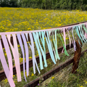 Pastel ribbon streamer on a wooden fence with a field of yellow flowers in the background