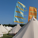 White tents with colourful flags against a blue sky