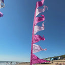 A pink festival-themed flag on a beach fluttering in the wind